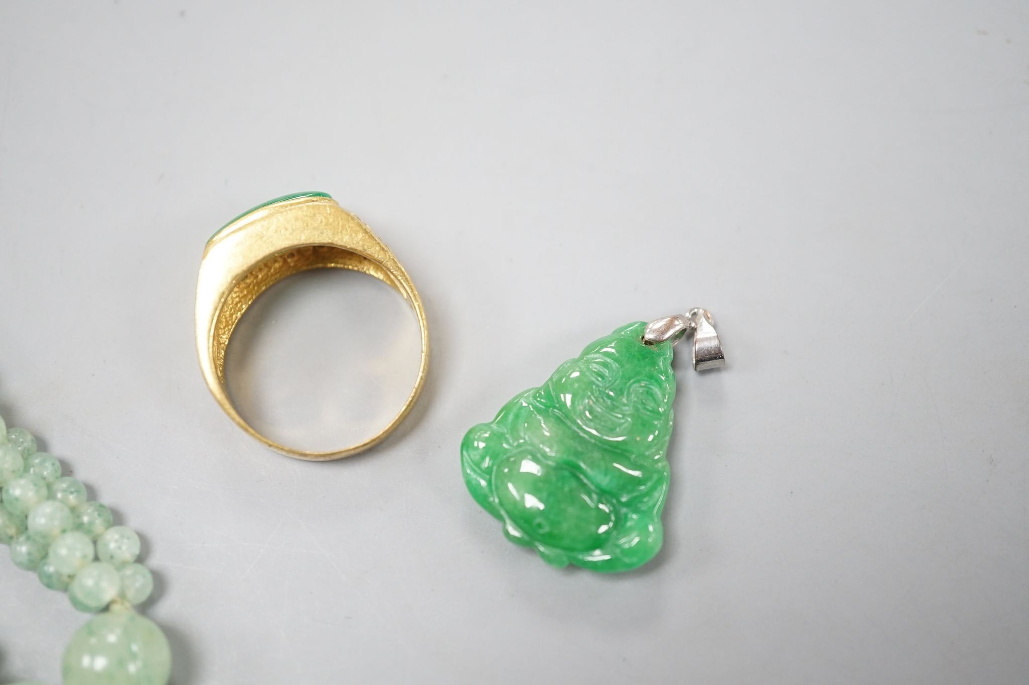 A carved jade pendant, 53mm on a quartz bead necklace, one other jade pendant and a jade, paste and gilt metal ring.